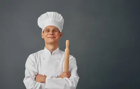 Шеф-повар с кухонными принадлежностями обслуживает профессионалов ресторанного дела