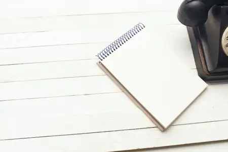 Ретро-телефон и блокнот на деревянном столе, вид сверху