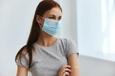 Пациент в медицинской маске с пластырем на руке, паспорт вакцинации от COVID-19 и здравоохранение