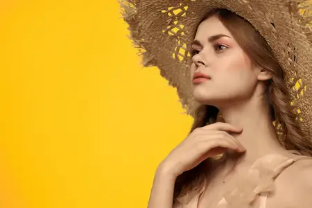 Симпатичная женщина в пляжной шляпе и купальнике, летний образ жизни, мода на жёлтом фоне