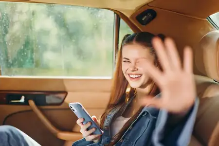 Счастливая девушка в машине, увлечённая смартфоном, излучает позитив и энтузиазм