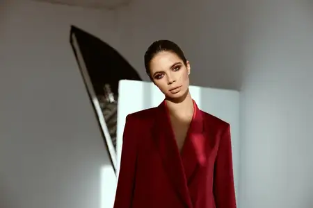 Экстравагантная женщина в красной куртке на фоне яркого света