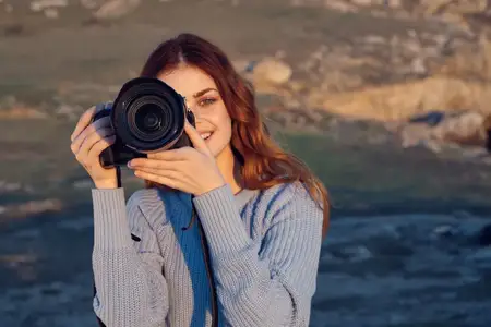 Жизнерадостная женщина-фотограф с камерой на фоне природы, пейзаж, образ жизни
