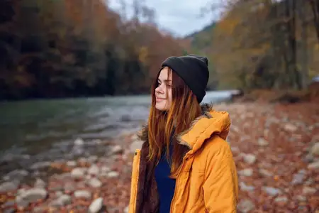 Женщина в желтой куртке в осеннем лесу, опавшие листья, река