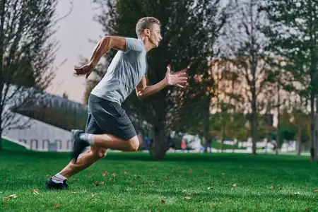Спортивный мужчина на открытом воздухе занимается бегом, физической активностью и упражнениями на лужайке