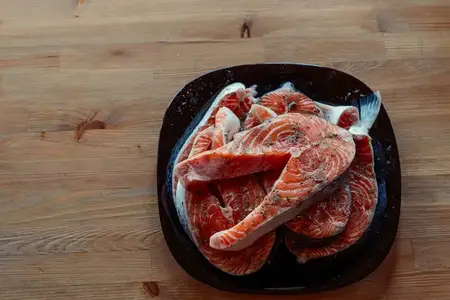 Маринованная красная рыба на тарелке на деревянном фоне