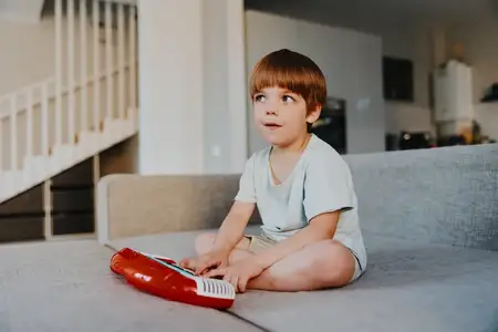 На этом изображении запечатлен счастливый мальчик, играющий с игрушечной клавиатурой, погруженный в музыку и творчество