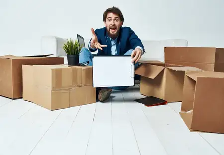 Менеджер переезжает на новое место работы, перенося картонные коробки с вещами в офисе
