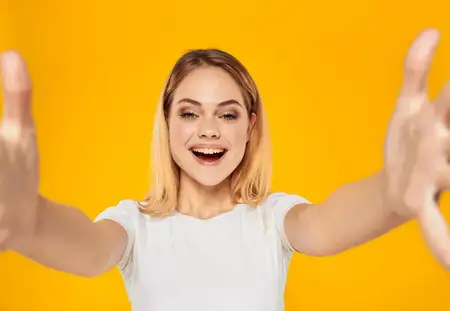 Женщина жестикулирует руками на жёлтом фоне