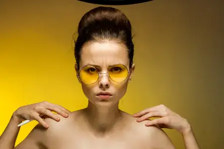 Красивая женщина с обнаженными плечами в желтых очках, излучающая моду, эмоции и очарование