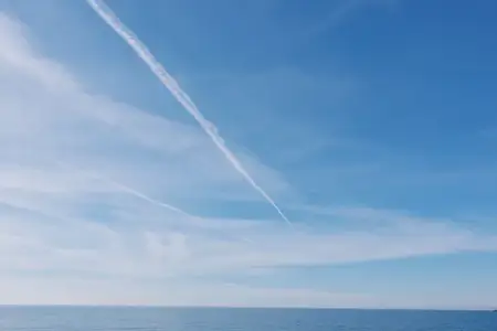 Безмятежный морской пейзаж с ясным голубым небом, бескрайним океаном и лёгкими облаками с ярким инверсионным следом самолёта, идеально подходит для редакционных, жизненных или вдохновляющих…