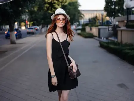 Симпатичная женщина в шляпе позирует на улице летом