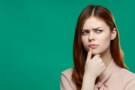 Красивая женщина демонстрирует эмоции, держа руку возле лица на фоне косметической студии с зелёным фоном