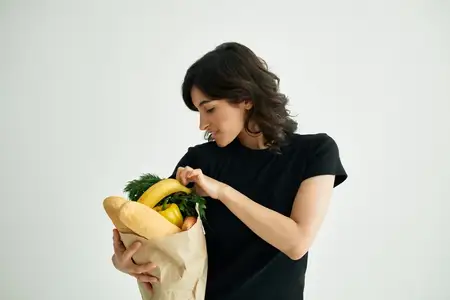Веселая брюнетка совершает покупки продуктов в магазине, здоровая еда