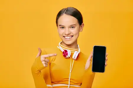 Активная женщина в фитнес-одежде с наушниками и смартфоном подчеркивает цифровое обучение, планирование тренировок и современный спортивный образ жизни в яркой студийной обстановке