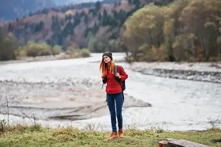 Турист с рюкзаком на берегу реки в горах, утренний пейзаж, модель, туризм