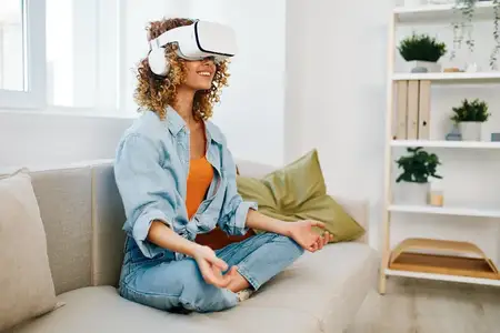 Улыбающаяся женщина наслаждается игрой в виртуальной реальности на диване в современной гостиной