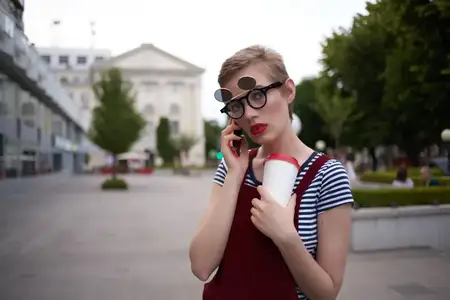 Симпатичная женщина в очках разговаривает по телефону на улице