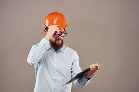 Бизнесмен в оранжевой краске работает с документами на бежевом фоне, что отражает индустриальный стиль жизни