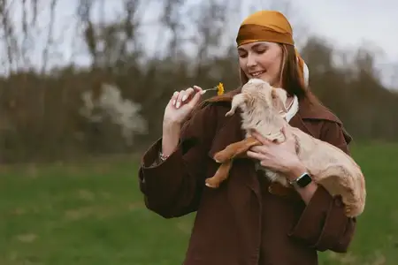 Естественный момент, показывающий нежное взаимодействие между опекуном и молодым козленком на открытом воздухе при ярком свете