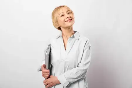 Пожилая женщина улыбается, держит ручку для письма