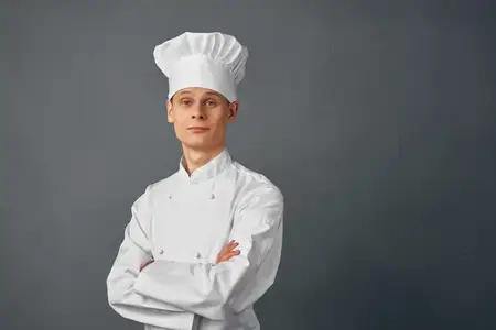 Профессиональный повар-мужчина работает на кухне ресторана на тёмном фоне