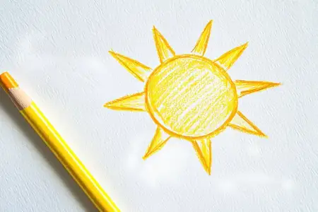 Веселая иллюстрация желтого солнца, выполненная цветным карандашом на белой бумаге, передающая яркую летнюю энергию, идеально подходит для детских проектов, образовательного контента или сезонных тем