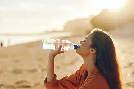 Женщина пьёт воду на открытом воздухе