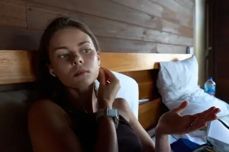 Портрет задумчивой женщины в постели с деревянными панелями, мягкий свет, умиротворённое настроение, повседневный стиль, интимная домашняя сцена, крупный план лица и рук, безмятежная атмосфера и…