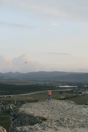 Запуск воздушного змея на каменистой вершине холма с живописной долиной на заднем плане