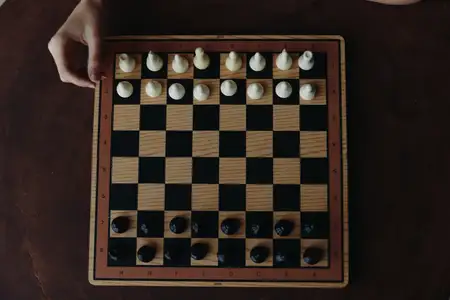 Напряжённая концентрация человека, играющего в стратегическую партию в шахматы на чёрно-белой клетчатой доске