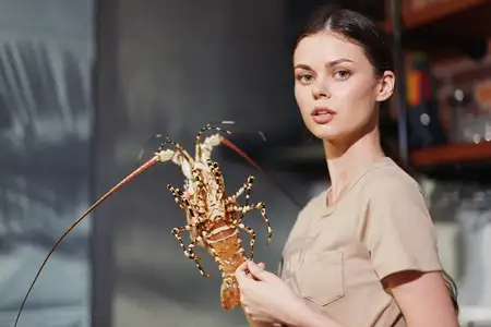 Женщина держит живого омара на кухне