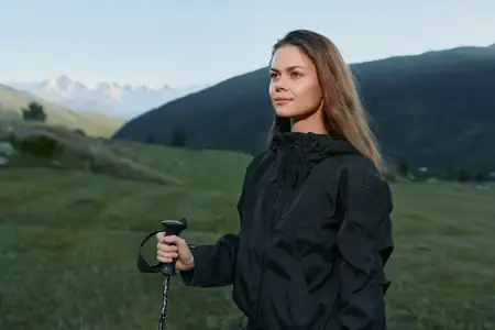 Спокойный турист смотрит на горизонт, а за его спиной разворачиваются альпийские пейзажи, приглашая к приключениям и исследованиям на широкой природе и свежем воздухе в яркий день