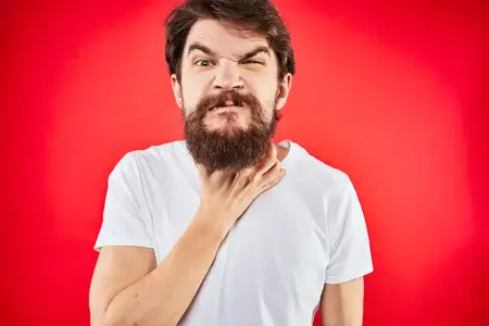 Мужчина в футболке и красной униформе в студии жестикулирует руками, выражая недовольство