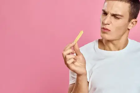 Милый мужчина с картошкой фри в руках, эмоции, модель, фастфуд, розовый фон, обрезанный вид, крупный план