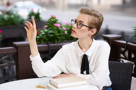 Студент с книгой в руках читает на прогулке, наслаждаясь свежим воздухом и общением