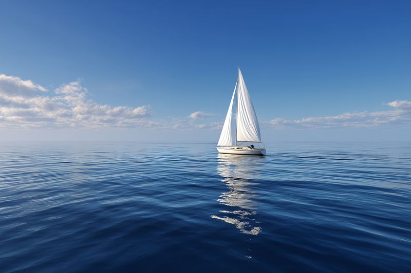 A lone sailboat glides across a calm open ocean under a clear blue sky, white sails catching sunlight and reflecting on gentle rippling water, creating a serene nautical scene.