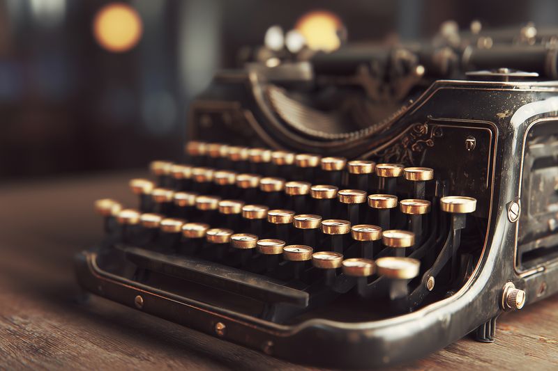Close-up of a vintage mechanical typewriter with worn keys on a wooden table, shallow depth of field and warm bokeh lighting creating nostalgic, timeless atmosphere.