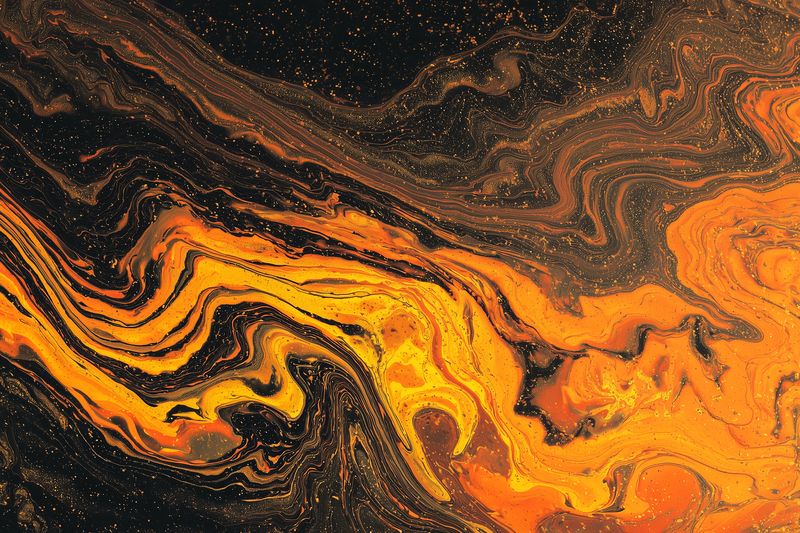 Abstract fluid artwork featuring vibrant orange and deep black marble swirls with metallic gold speckles, creating a dramatic textured background for creative design use.