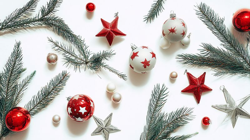 Flat lay of red and silver Christmas ornaments with star decorations and fir branches on a white background, seasonal holiday composition for festive design and winter celebration projects.