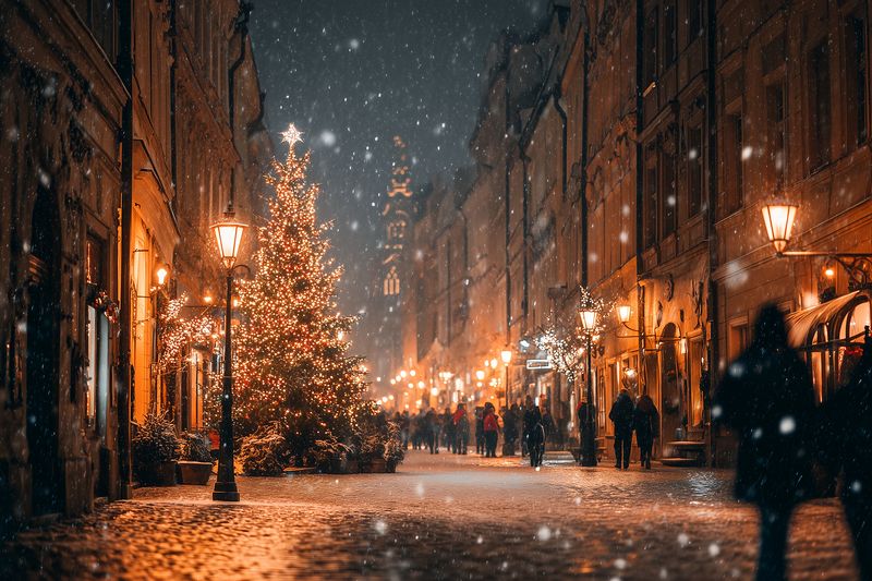 Christmas tree, snowy street, holiday lights, evening warm glowing lanterns and falling snow create a festive nighttime street scene in an old town square