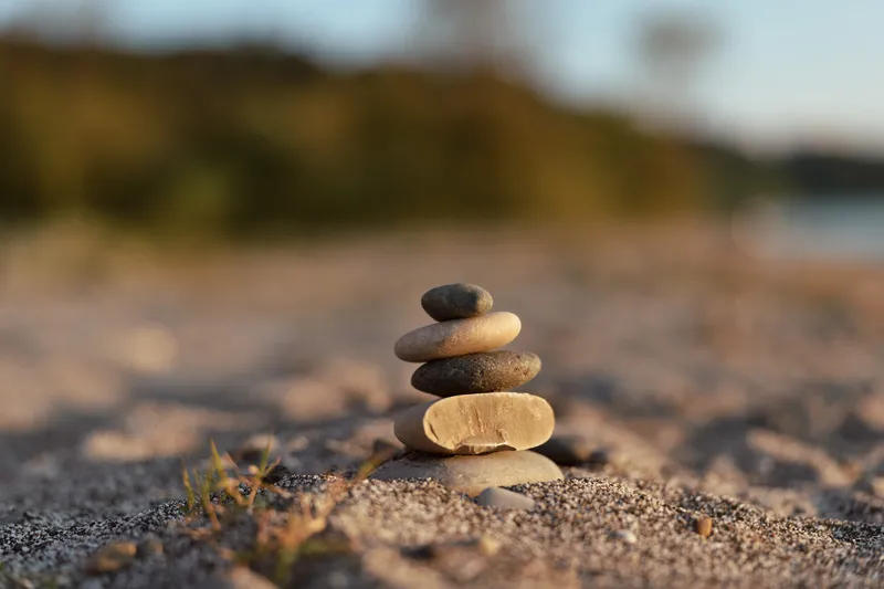 Balanced stones zen stack on a sandy beach during sunset. This calm composition represents meditation, harmony, lifestyle, and relaxation for a peaceful soul in nature outdoor area.